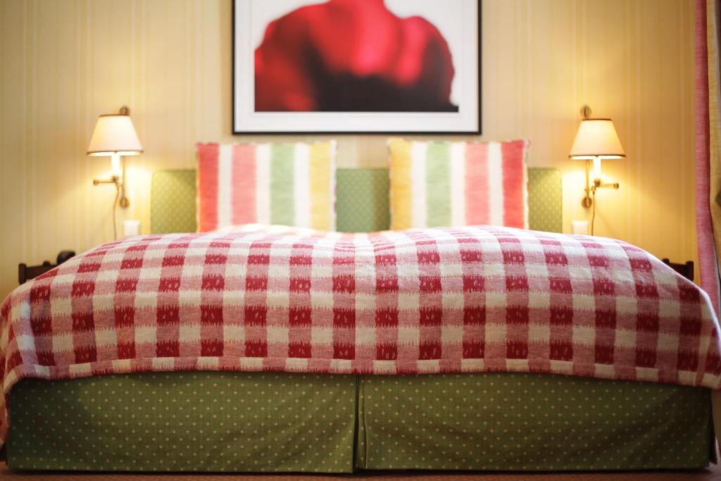 a bed with a red and white checkered blanket at Hotel Stadt Hamburg in Westerland