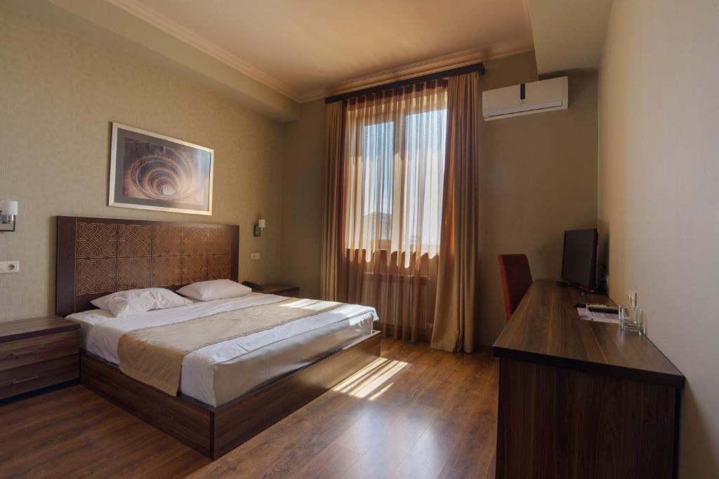 um quarto com uma cama, uma secretária e uma televisão em Kantar Hotel em Yerevan