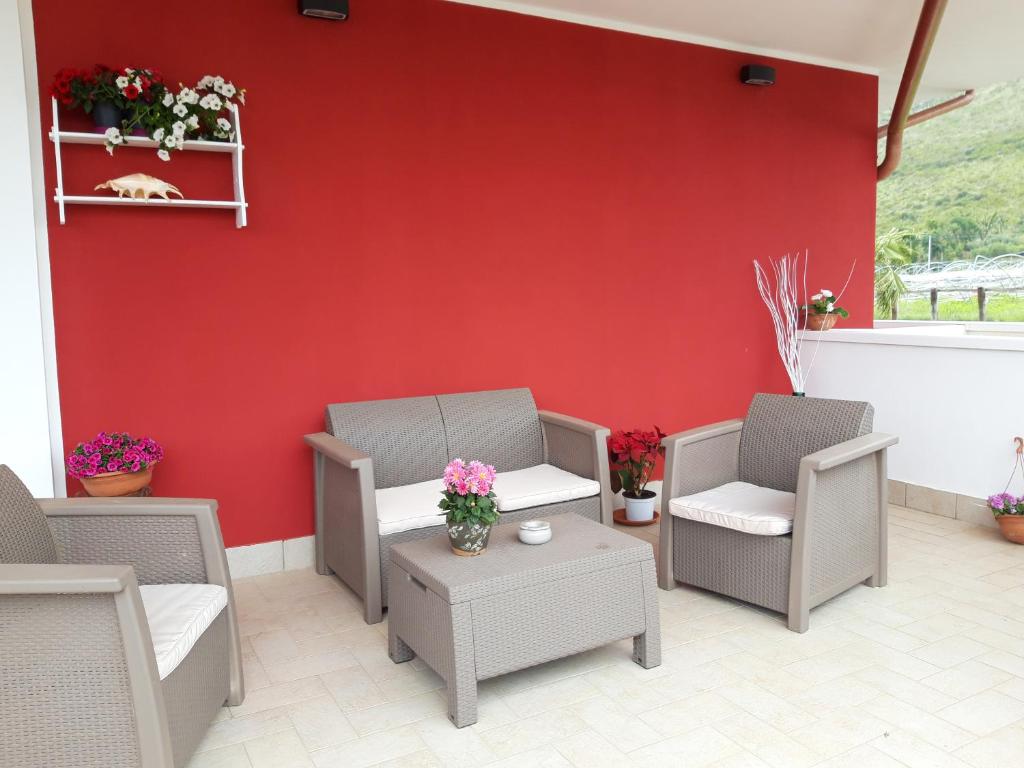 a red wall with chairs and a table with flowers at Valeri 's Country House in Sperlonga
