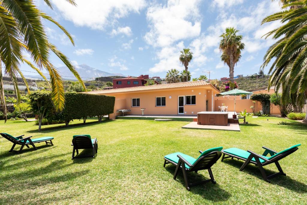 einen Garten mit Stühlen und ein Haus mit Palmen in der Unterkunft Finca La Gaviota - Las Palmeras in Icod de los Vinos
