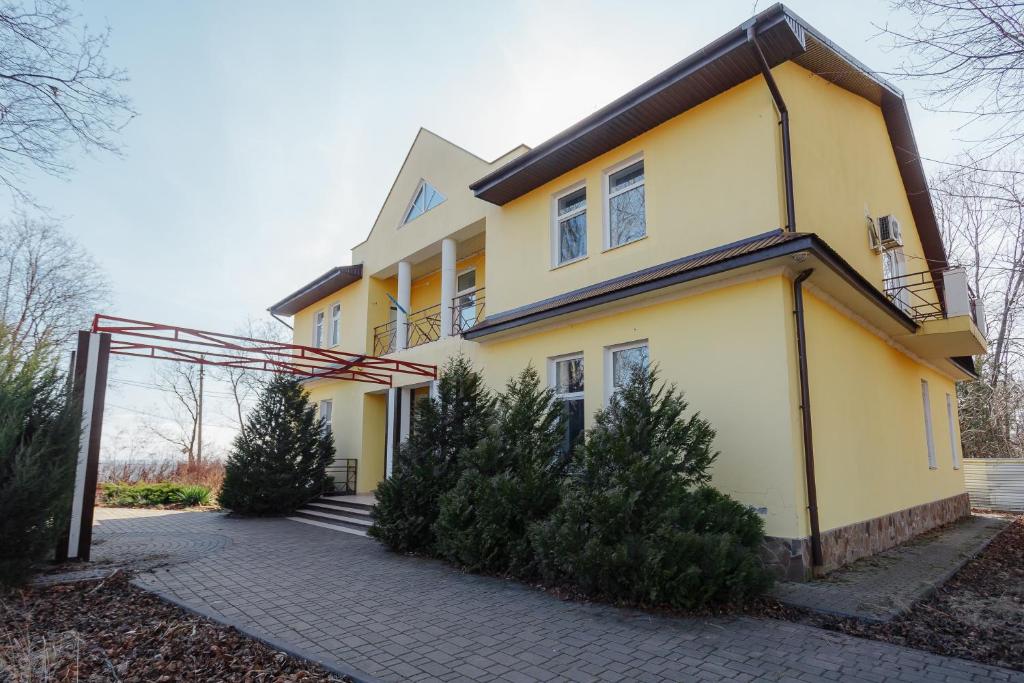 a yellow house with trees in front of it at Гостевой дом писателей in Odesa