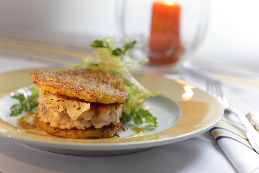 a white plate with a sandwich and salad on a table at Hotel Stadt Hamburg in Westerland