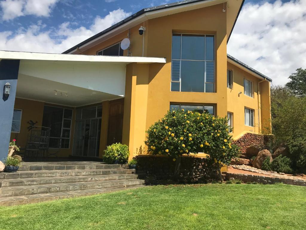 a yellow house with a lawn in front of it at The Farmhouse in Okahandja