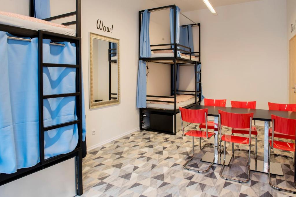 Cette chambre comprend une table et des chaises rouges. dans l'établissement Hostel Eleven, à Brno