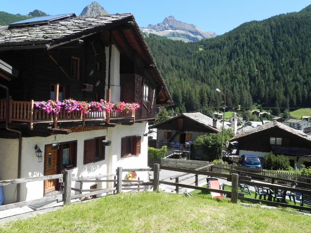 une maison avec des fleurs sur le balcon dans l'établissement Le Vieux Rascard Chambres d'Hotes, à Champoluc