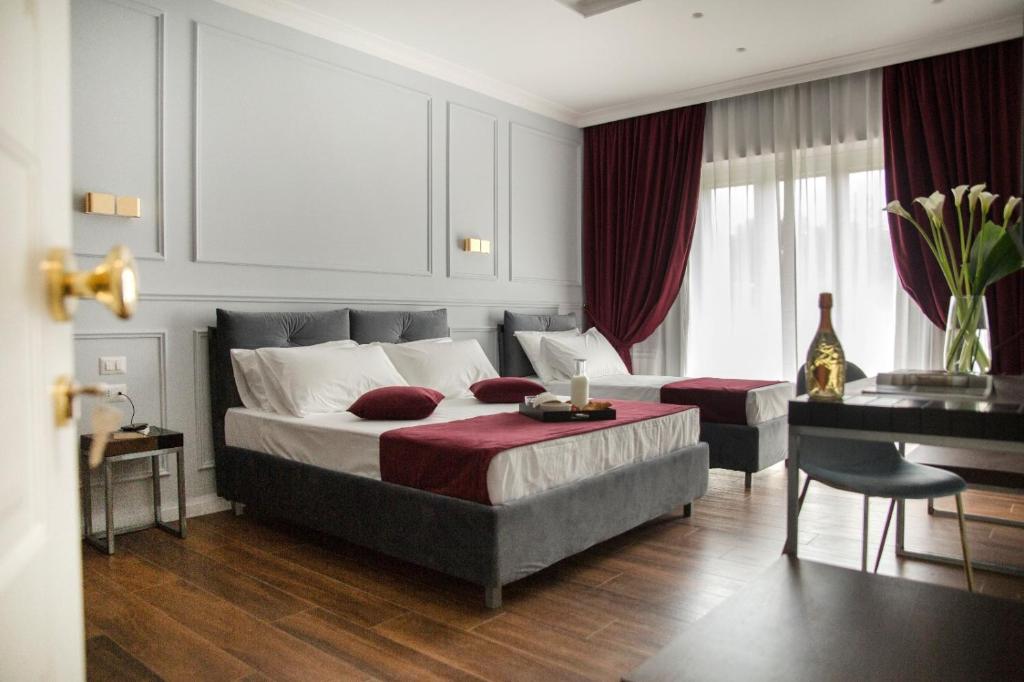 a bedroom with a large bed and a table and a desk at Unicum Roma Suites in Rome