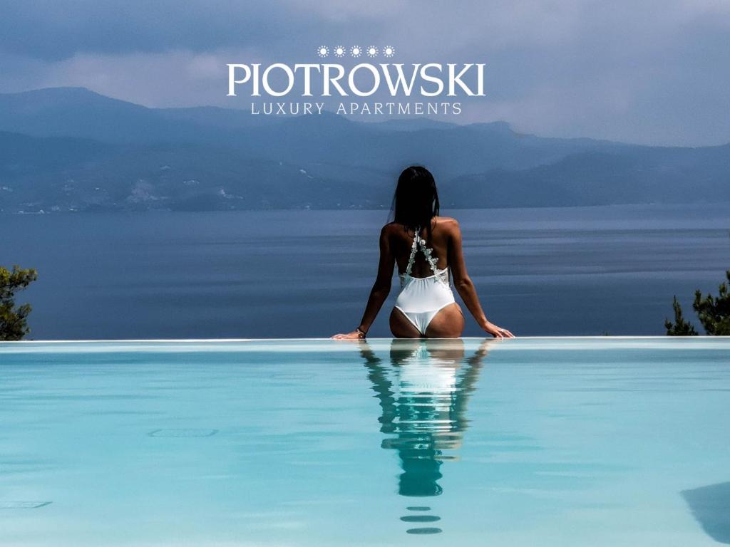 una mujer sentada en una piscina mirando hacia el agua en PIOTROWSKI APARTMENTS, en Theológos