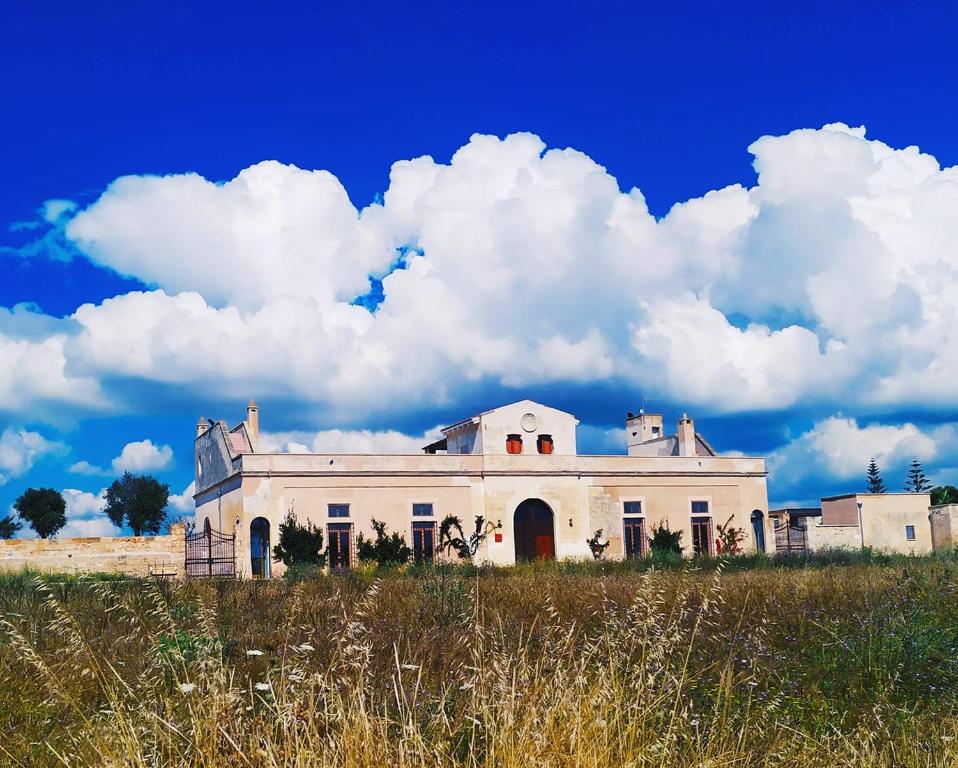 uma casa velha num campo com um céu nublado em Masseria Casina Bellanova em Porto Cesareo