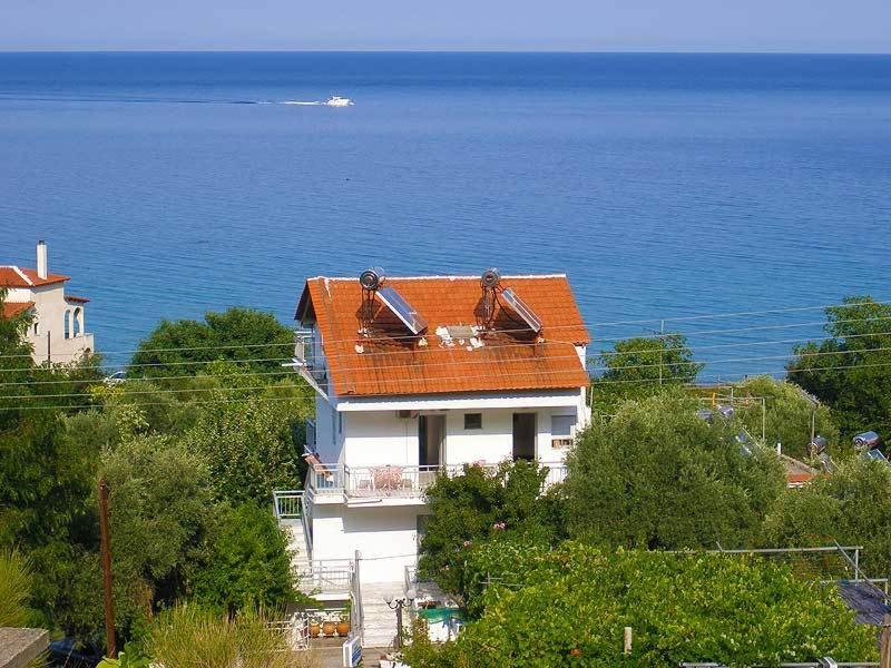 uma casa com um telhado laranja junto ao oceano em House Mantesos em Kinira