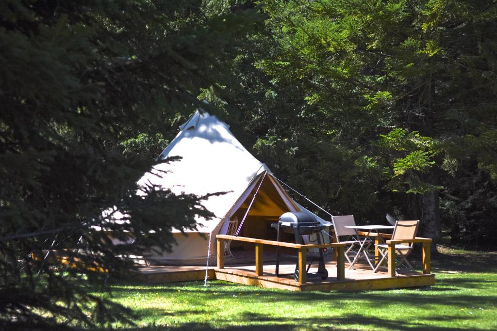 a tent with a table and chairs in a field at Glamping at Camping La Source in Saint-Pierre-dʼArgençon
