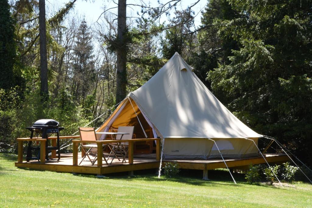 a tent with a grill and a chair in a field at Glamping at Camping La Source in Saint-Pierre-dʼArgençon