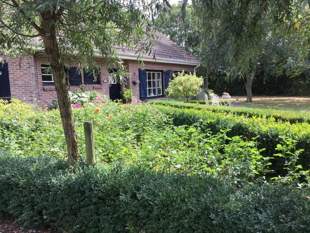 een bakstenen huis met een tuin ervoor bij Royale bovenwoning in Vlake