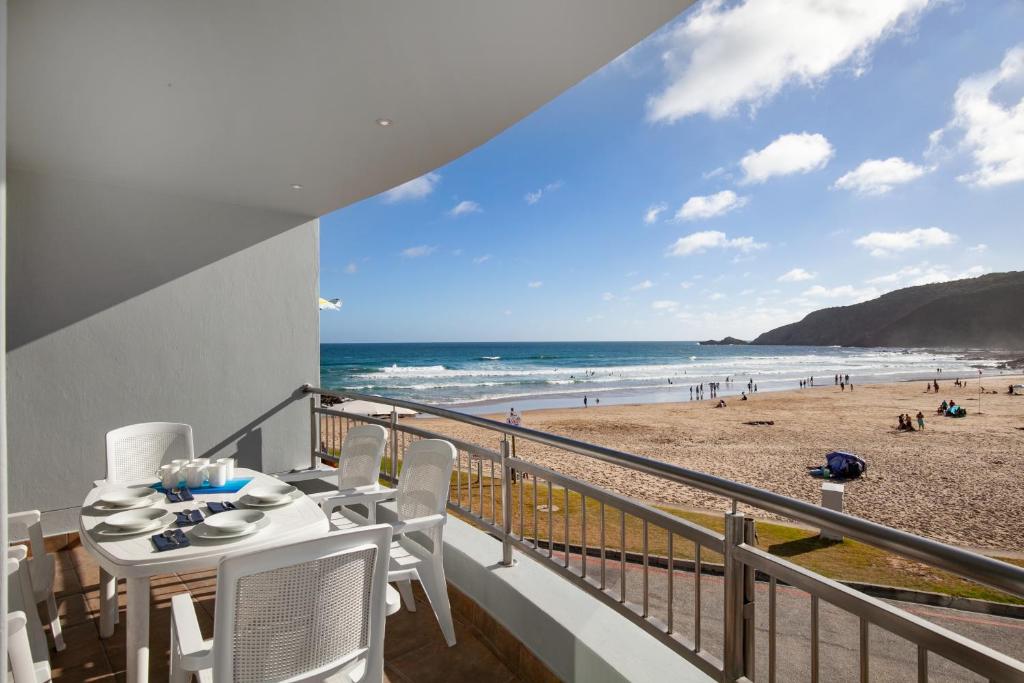 a balcony with a table and chairs and the beach at Makarios On Sea in Herolds Bay