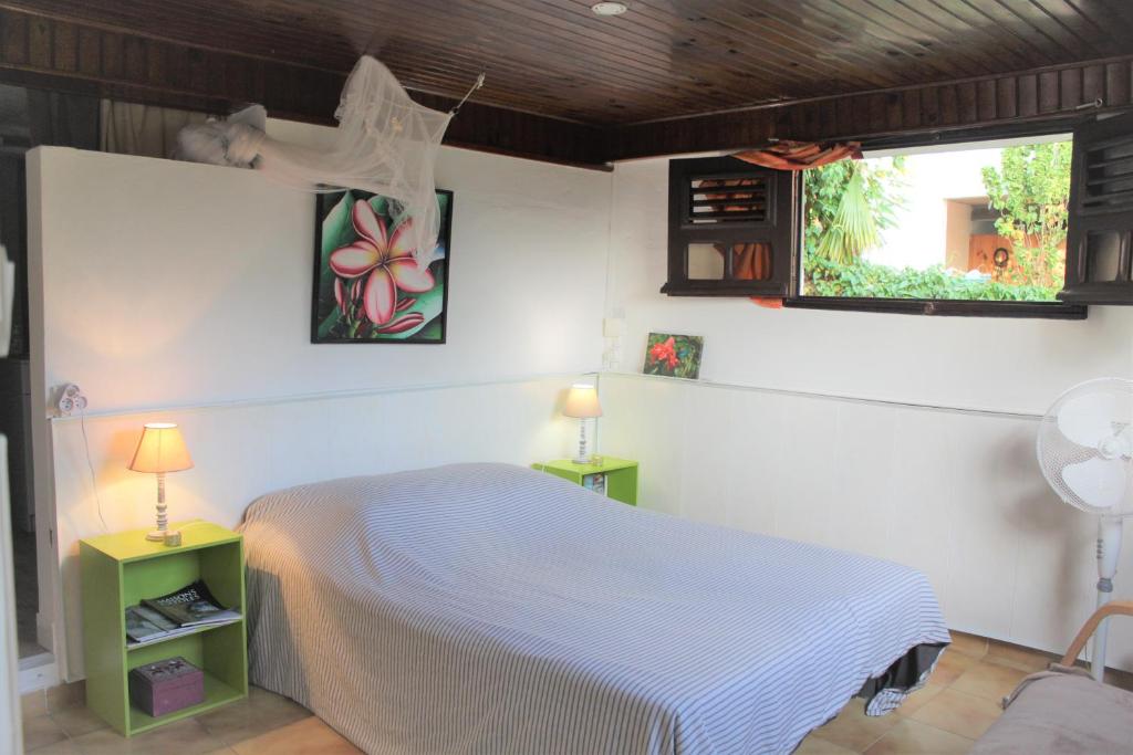 um quarto com uma cama, 2 candeeiros e uma janela em Gites "les colibris" em Schœlcher