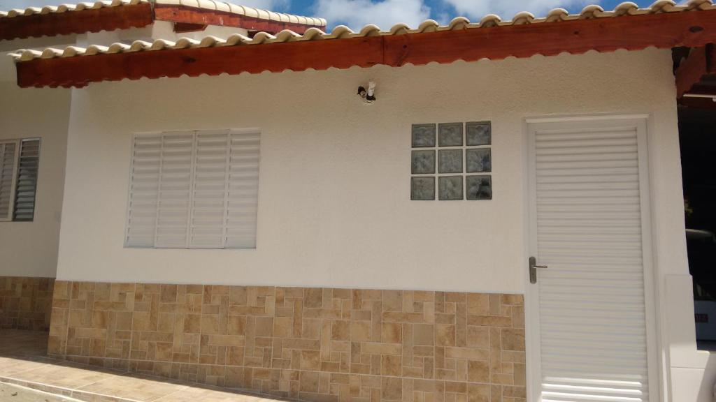 uma casa branca com uma janela e uma porta em Recanto das Videiras em Maria da Fé