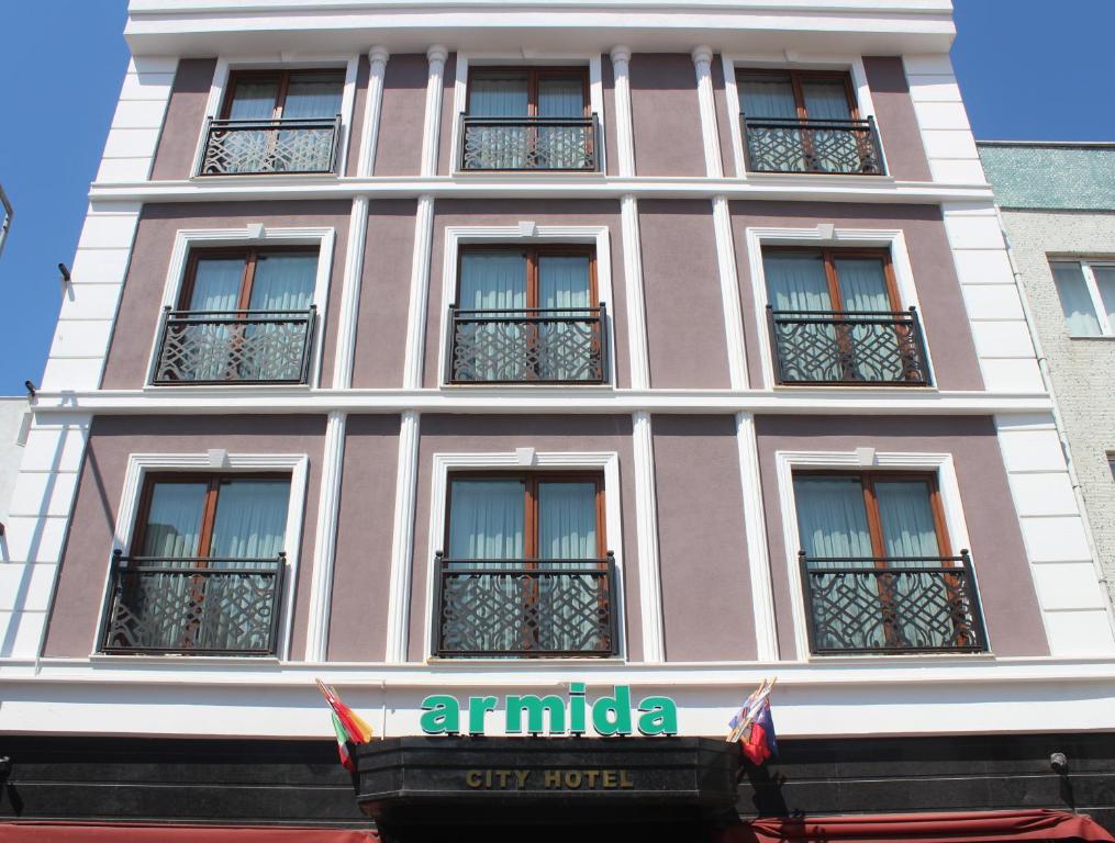 um edifício cor-de-rosa com janelas e um cartaz. em Armida City Hotel em Çanakkale