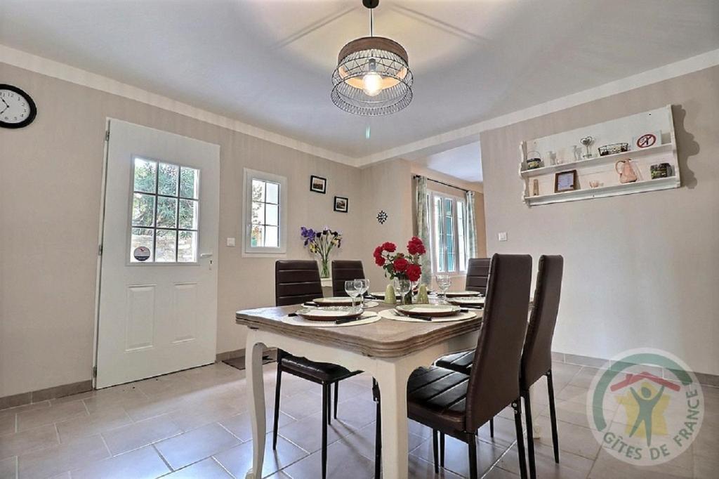 a dining room with a table and chairs and a clock at Gîte de l'Eclotine in Saint-Théodorit