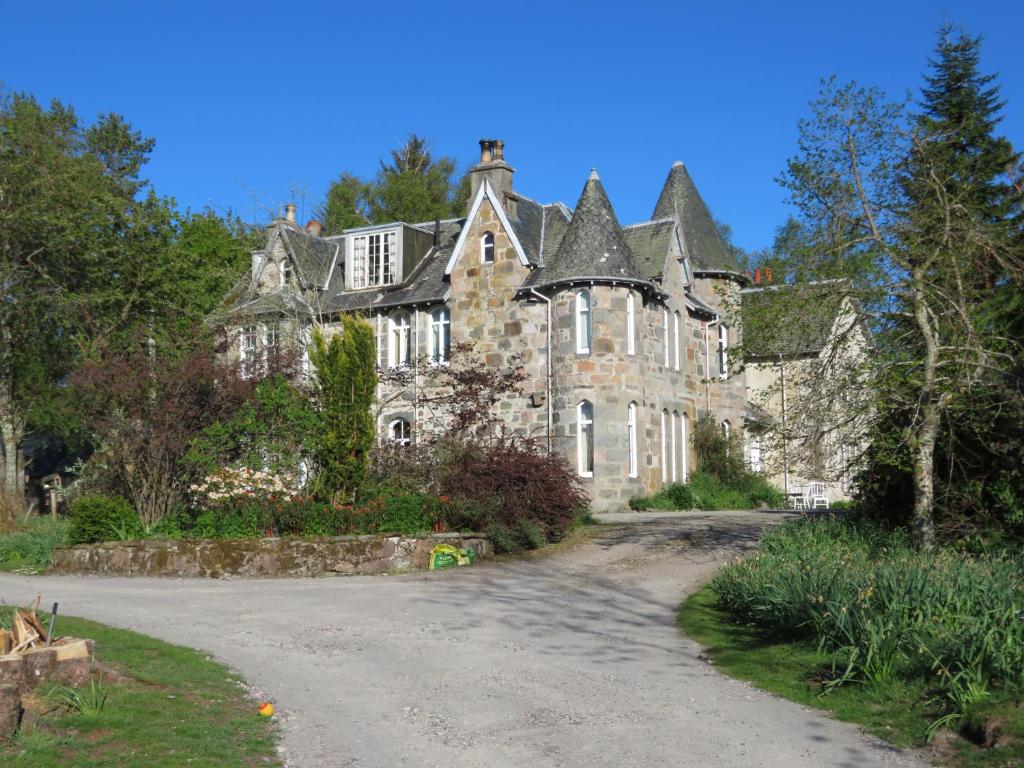 una vecchia casa in pietra con una strada davanti di Balvraid Lodge B&B a Inverness