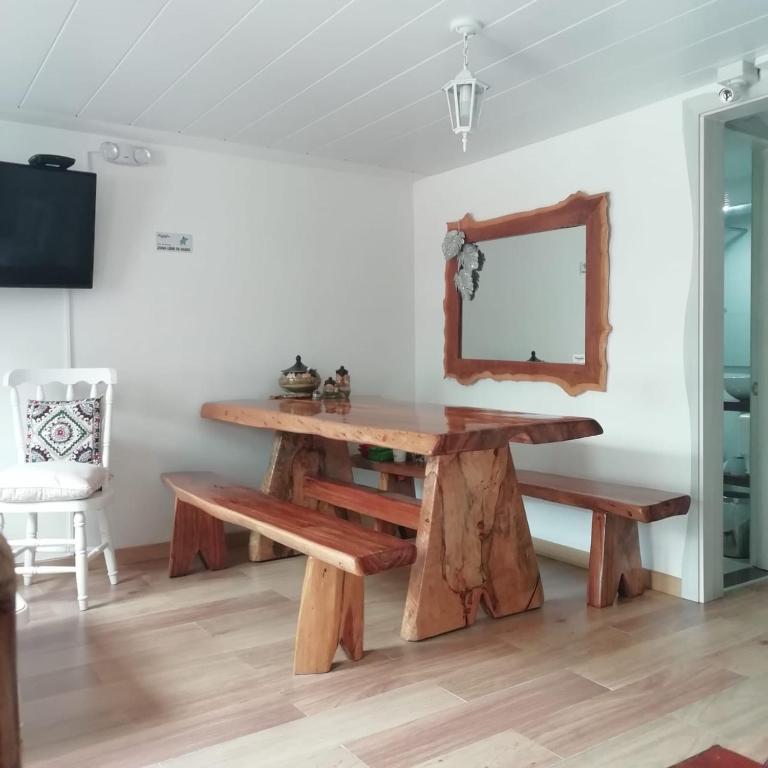a table and benches in a room with a mirror at Elizabetha Hostal in Salento