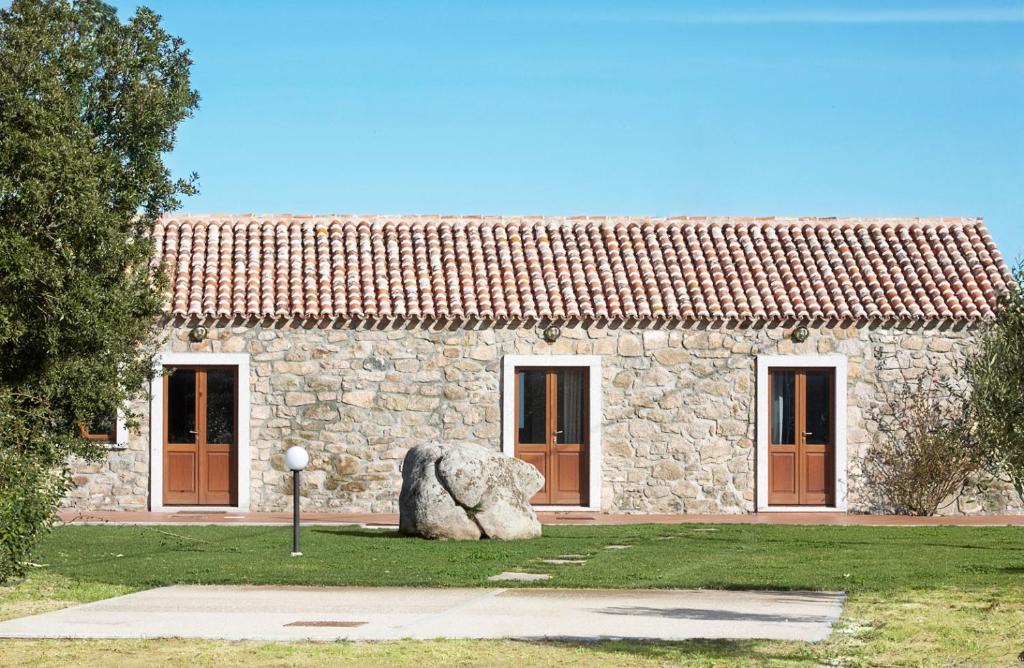 un edificio de piedra con una gran roca delante de él en La Littighedda, en Rena Majore