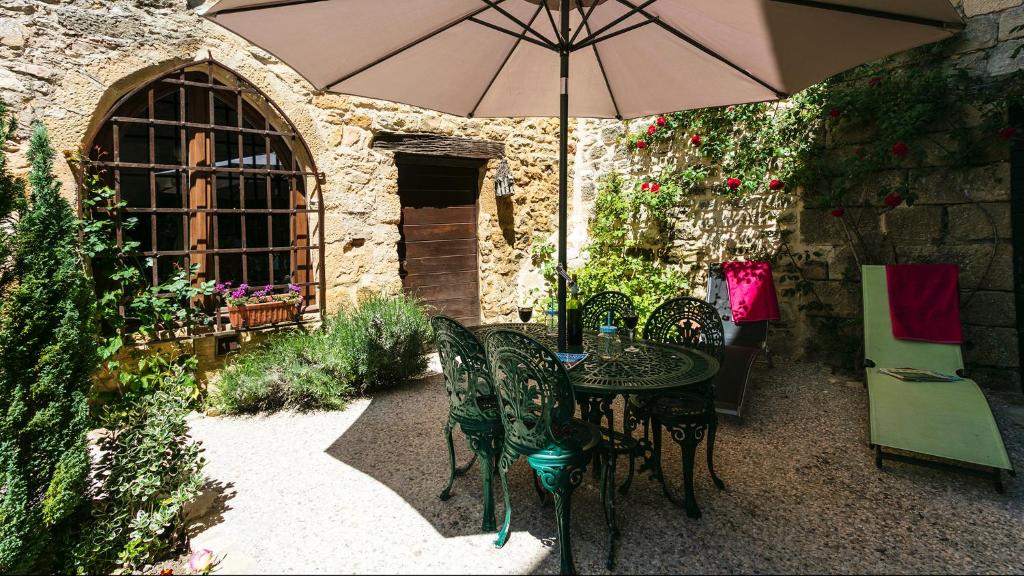 eine Terrasse mit einem Tisch und Stühlen mit einem Sonnenschirm in der Unterkunft Au coeur de Beynac, une maison de caractère avec jardin terrasse in Beynac-et-Cazenac