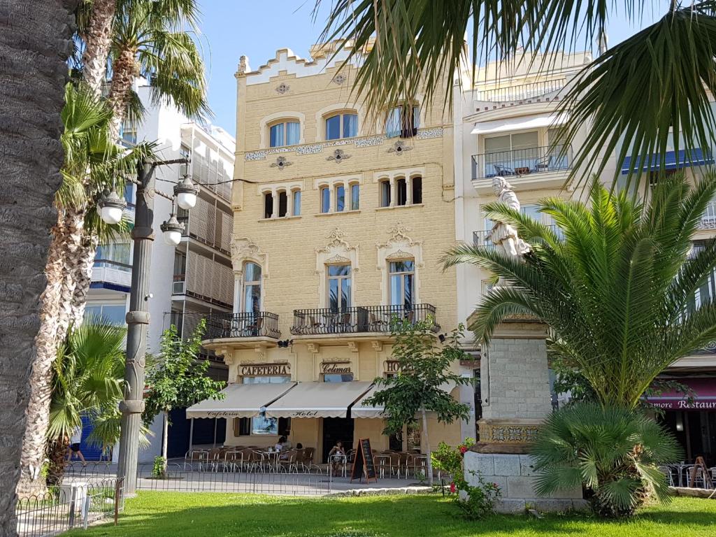 un gran edificio amarillo con un restaurante delante de él en Hotel Celimar, en Sitges