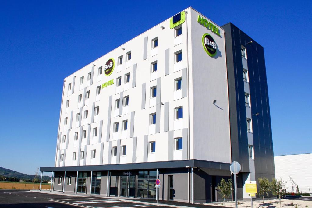 ein großes weißes Gebäude mit einem grünen Schild darauf in der Unterkunft B&B HOTEL Montélimar Sud in Montélimar