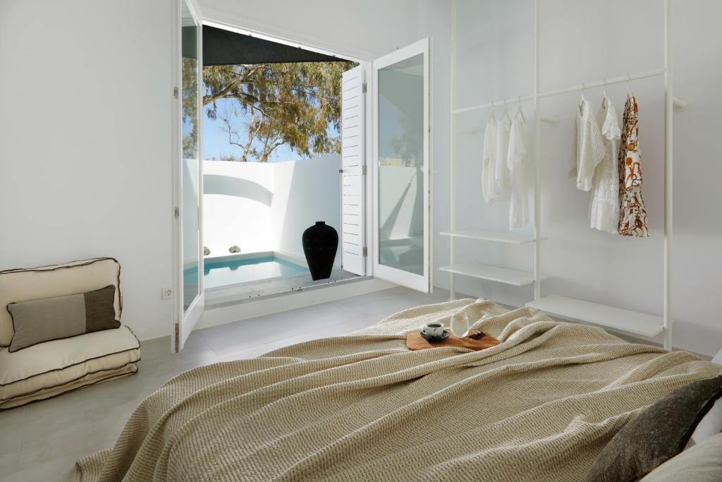 una camera con un grande letto e uno specchio di Le Blanc Nest Santorini - Family / Couples Luxury House a Mesariá
