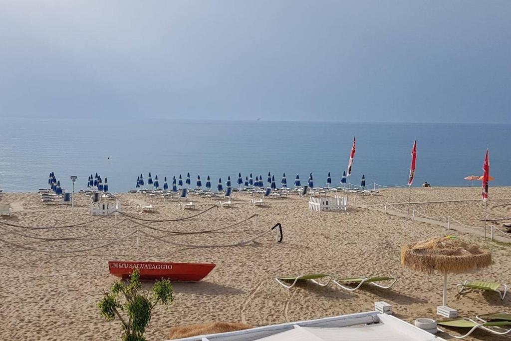 ein Strand mit vielen Sonnenschirmen und einem roten Boot darauf in der Unterkunft A due passi da una spiaggia meravigliosa in Crotone