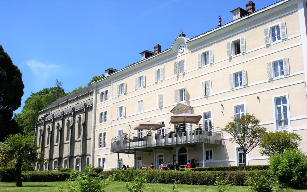 a large white building with a balcony with umbrellas at Domaine Agerria in Mauléon-Licharre