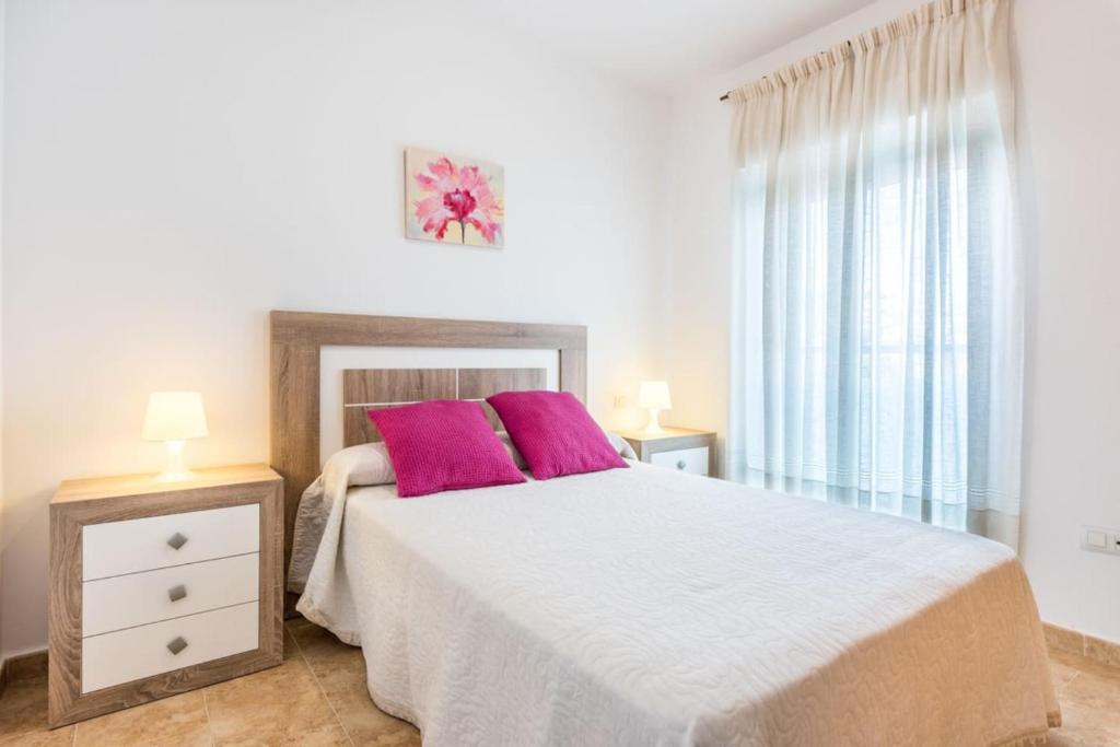 1 dormitorio con 1 cama grande y 2 almohadas rosas en COMFORTABLE, CLOSE TO THE BEACH, POOL, NEW, PADDLE, en Rincón de la Victoria