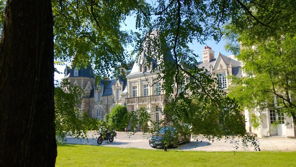 une grande maison avec un arbre en face dans l'établissement Château du Bois de La Noe, à Bouaye