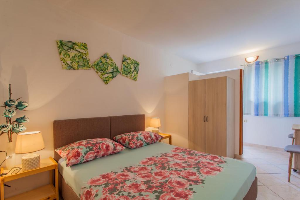 - une chambre avec un lit orné de fleurs sur le mur dans l'établissement Rooms Mužić, à Cres
