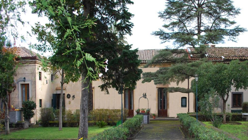 Une grande maison blanche avec des arbres dans la cour dans l'établissement Case Zuccaro, à Trecastagni