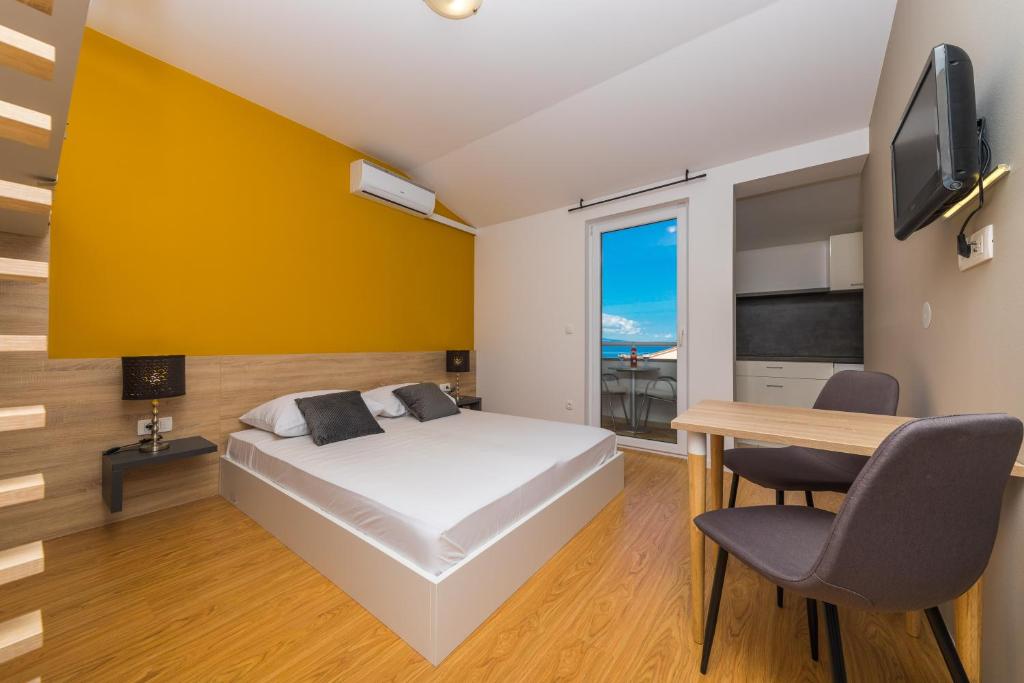 een slaapkamer met een bed, een bureau en een televisie bij Apartments Gavran in Baška Voda