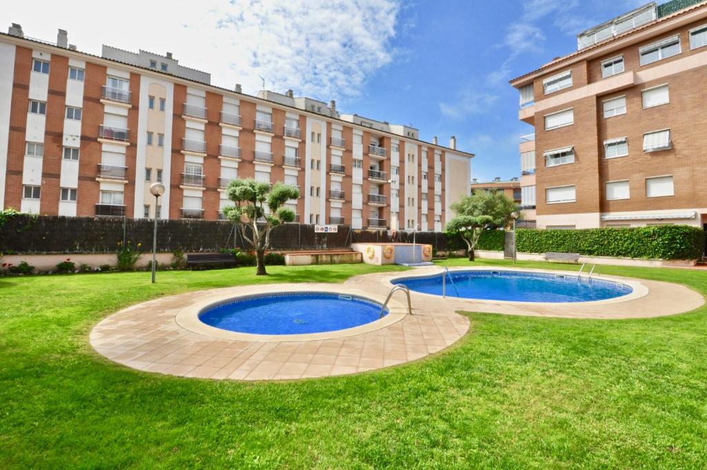 une cour avec 2 piscines en face d'un bâtiment dans l'établissement Apartment Didier, à Lloret de Mar