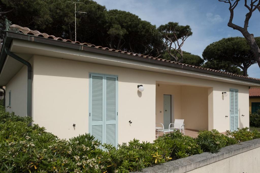 Una casa blanca con persianas azules. en Villetta Lorenza, en Marina di Grosseto