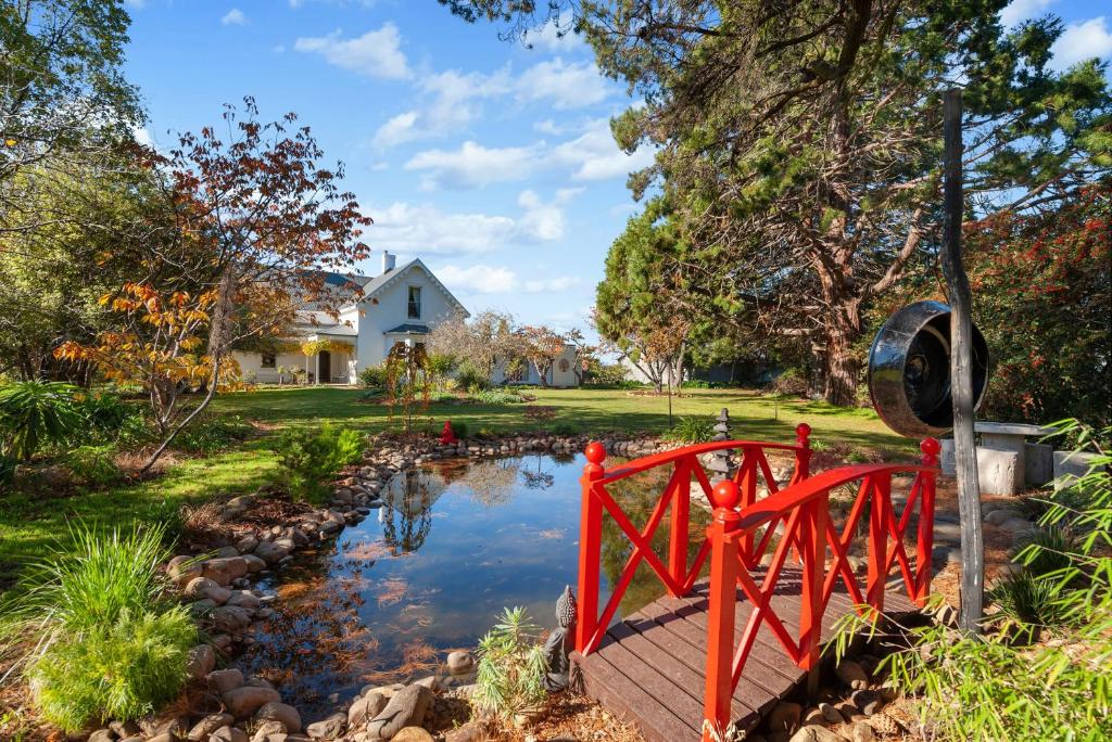 a red bridge over a pond in front of a house at Belmont Homestead in Swansea