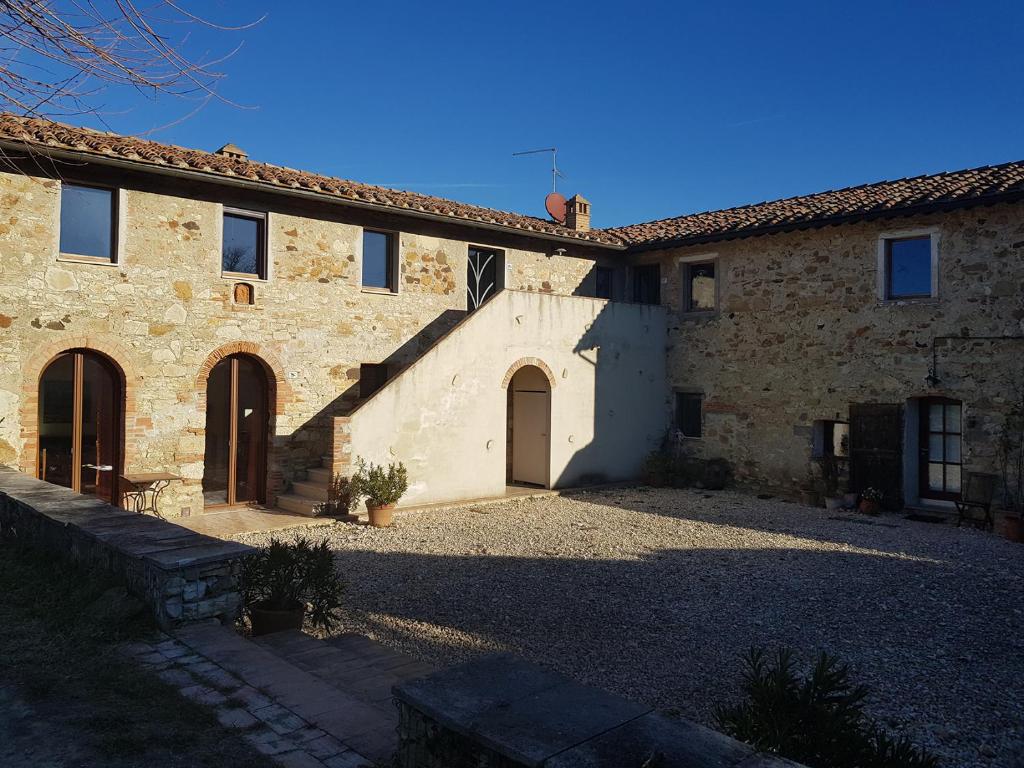 a large stone building with two doors and a courtyard at Podere Bisciano in Lano