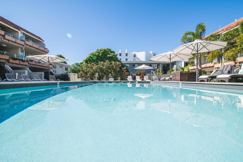 a large swimming pool with chairs and an umbrella at Hotel Laguna in Noosa Heads