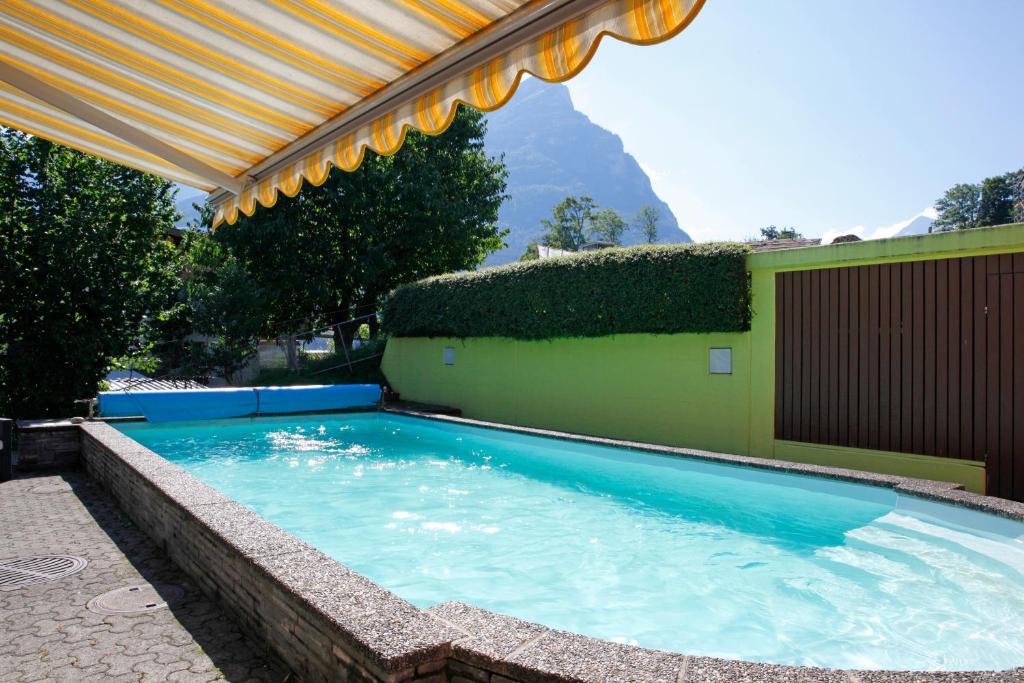 a swimming pool with a pergola next to a building at Hotel Krone in Attinghausen