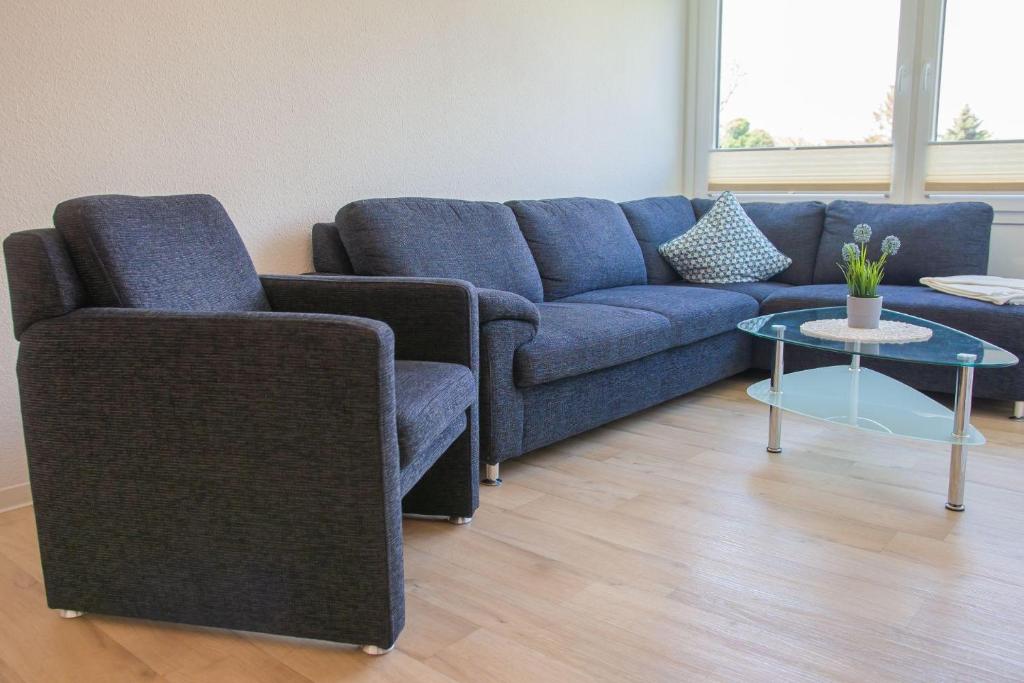 a living room with a blue couch and a table at Haus Strandburg Dünengras in Dahme