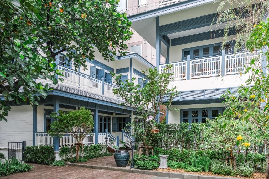 an apartment building with a balcony and trees at Baan Vajra in Bangkok