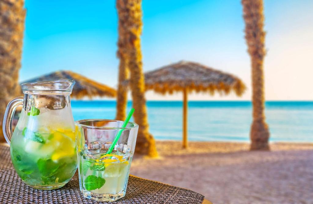 een drankje in een glas op een tafel op het strand bij Rich Luxury Suites in Eilat