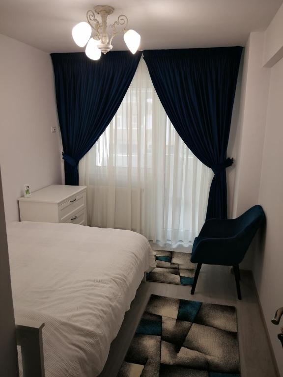 a bedroom with a bed and a chair and a window at Apartament Karina complex Bacovia in Bacău
