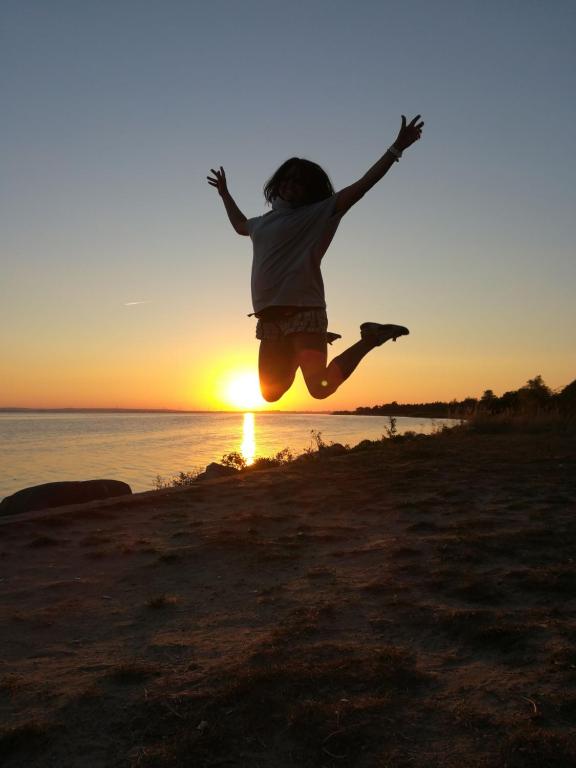 eine Person, die bei Sonnenuntergang am Strand in die Luft springt in der Unterkunft Przyczepa kemping Chałupy 3 Półwysep Hel in Chałupy