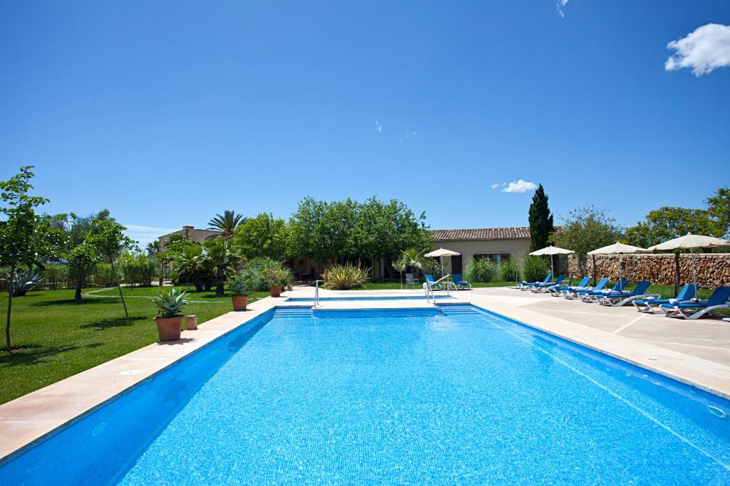 a swimming pool with chairs and a house at Agroturisme Na Martina in Portopetro