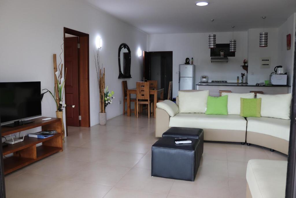 ein Wohnzimmer mit einem weißen Sofa und einem TV in der Unterkunft Mahina Luxury 2 Bedroom Apartment with Pool in Flic-en-Flac