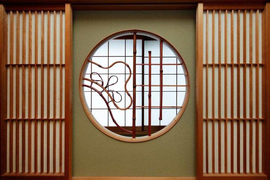 ein rundes Fenster an einer Wand mit einem Baum darin in der Unterkunft Ryokan ASAKUSA-chaka- in Tokio