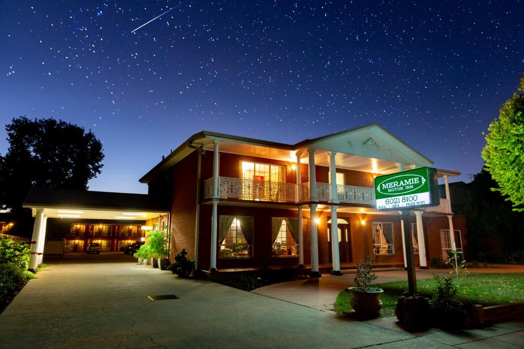 uma casa com uma placa à frente à noite em Meramie Motor Inn em Albury